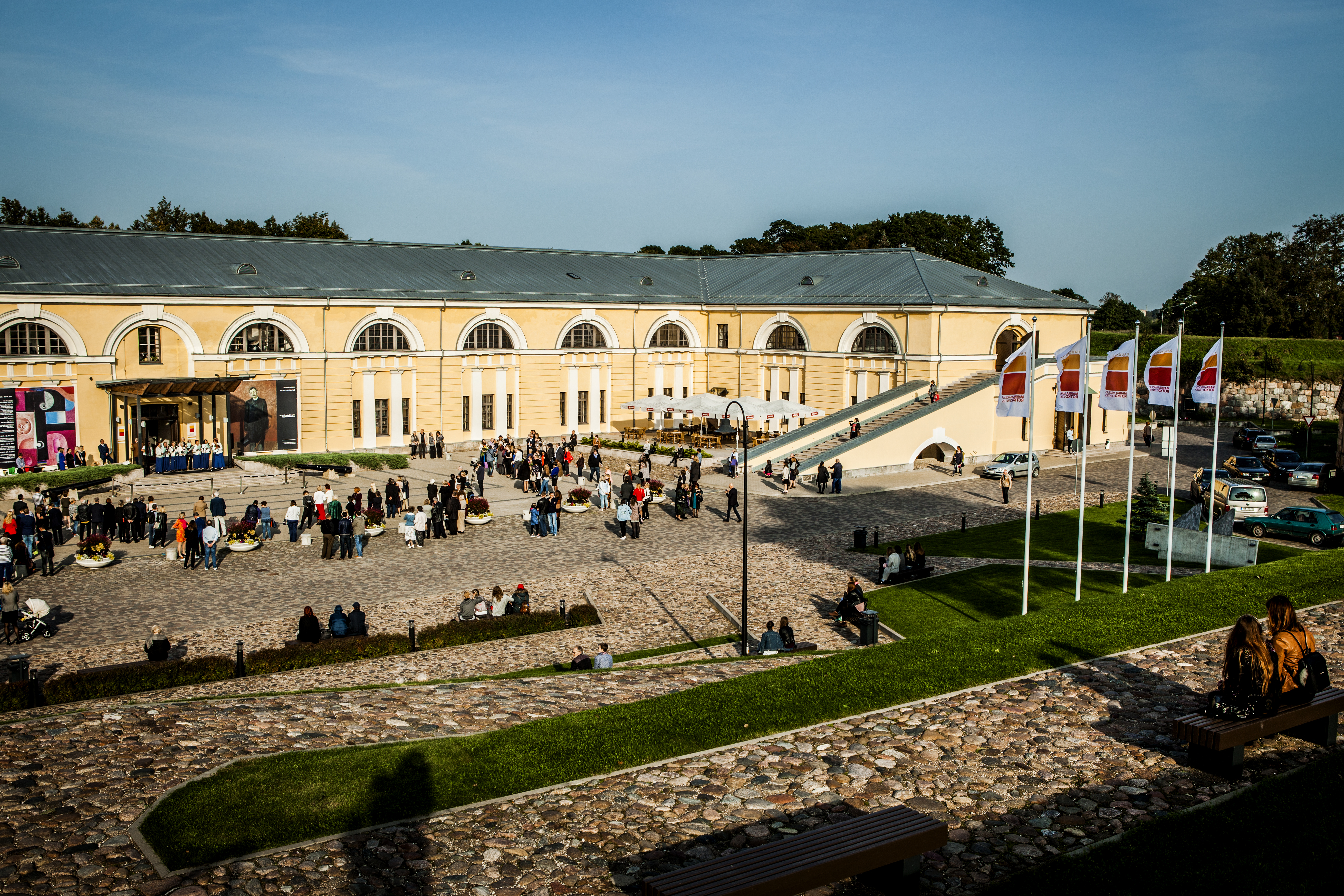Daugavpils Marka Rotko mākslas centrs, āra pagalms, kurā sapulcēju&scaron;ies cilvēki saulrietā