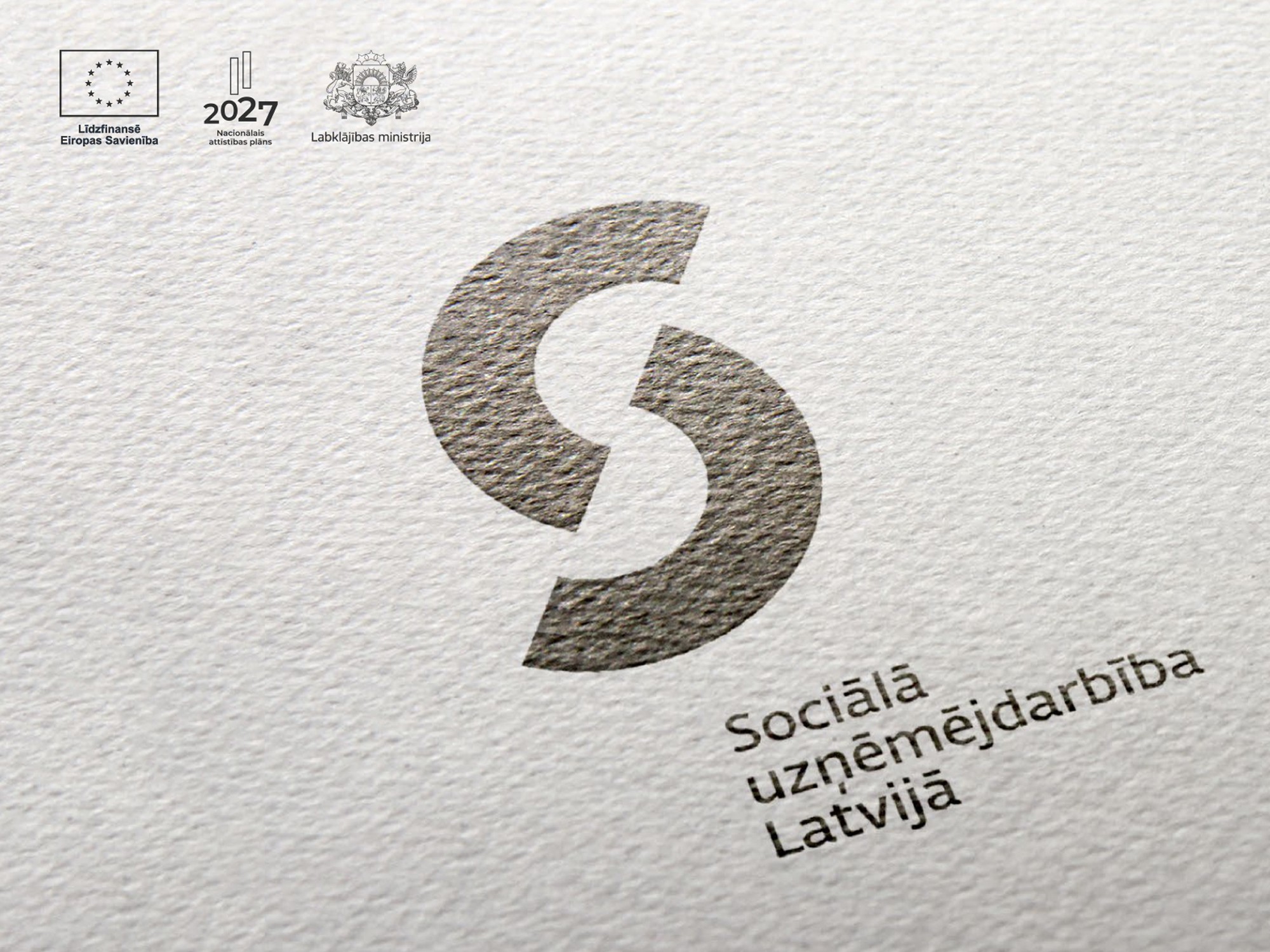 Uz reljefa papīra uzrdukāts melns logo "Sociālā uzņēmējdarbība Latvijā"