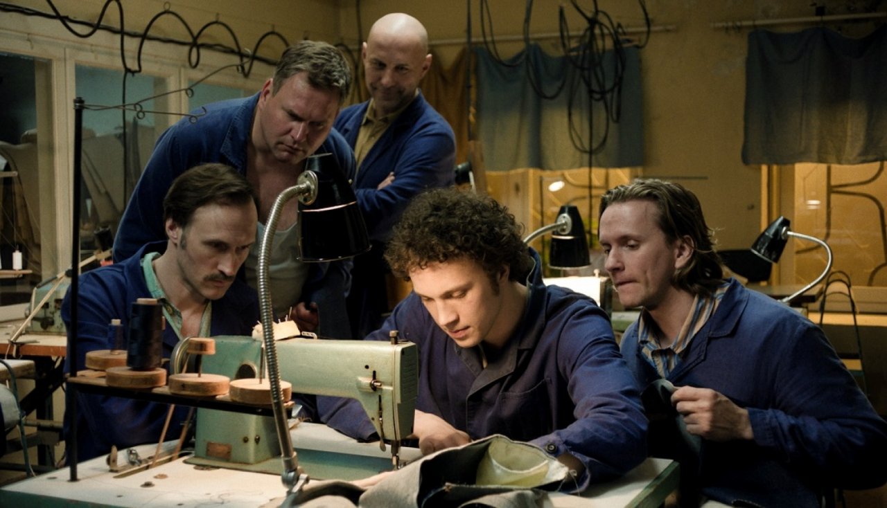 Five men sewing jeans at a sewing machine