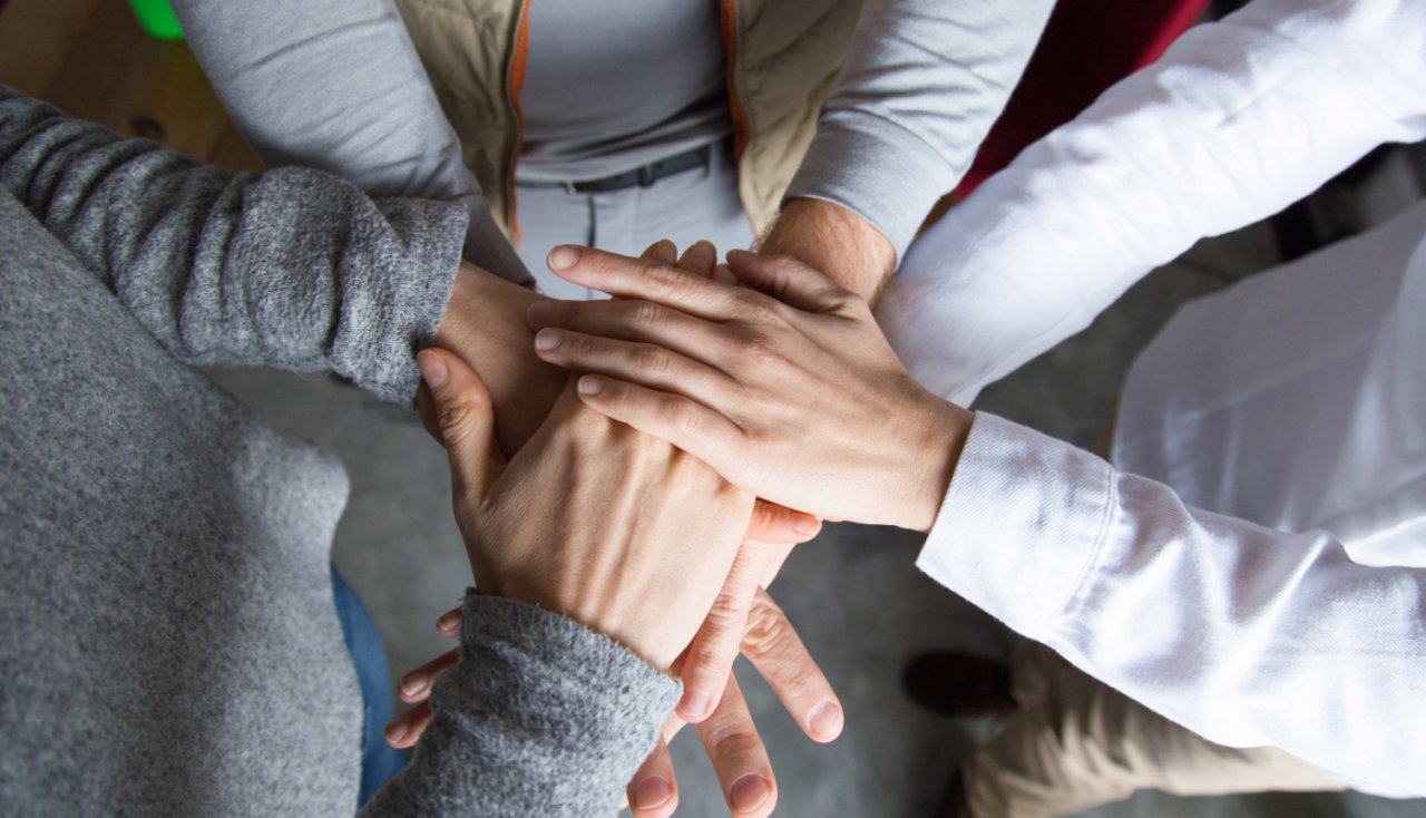Three hands placed on top of each other