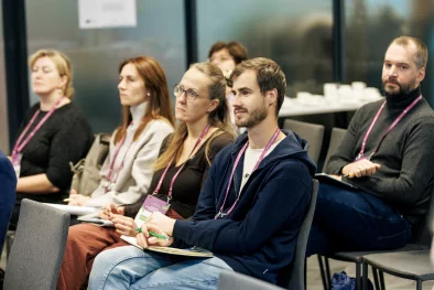 Auditorija vairāku cilvēku sastāvā sēž un vēro kaut ko