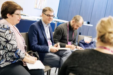 Cilvēki sēž krēslos un kaut ko lemj