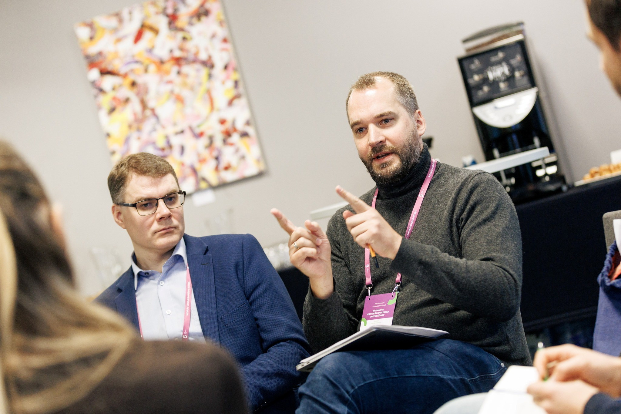 Vīrietis sēžot darba grupā skaidro savu viedokli