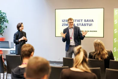 Vīrietis, uzņēmējs, smaidot prezentē auditorijai savu ideju