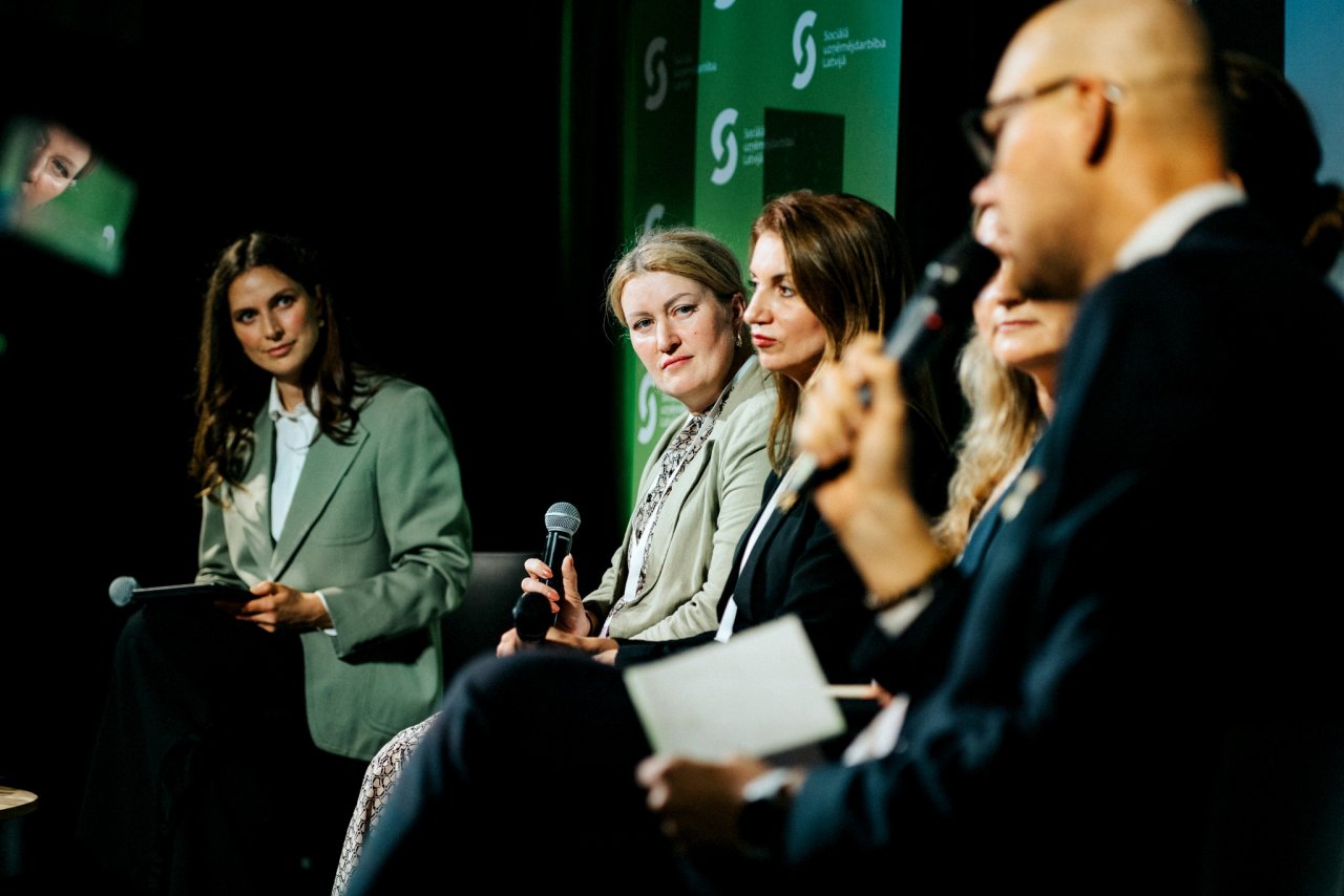 Vairākas pieaugušas sievietes un viens vīrietis uz skatuves sēž un debatē