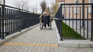 sieviete ratiņkrēslā ripinās lejā pa bruģētu pandusu