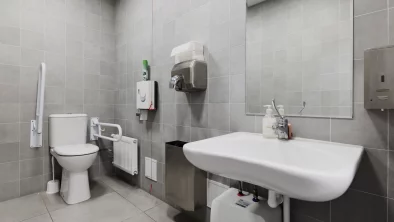 Labierīcību telpa. Redzama izlietne, spogulis, tualetes pods un citi tipiskie aksesuāri