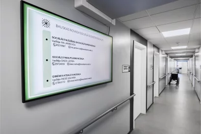 Pelēks koridoris ar daudz durvīm. Pie sienām margas. Uz sienas liels monitors ar informāciju par sociālo dienestu. Koridora vidū ratiņkrēsls.