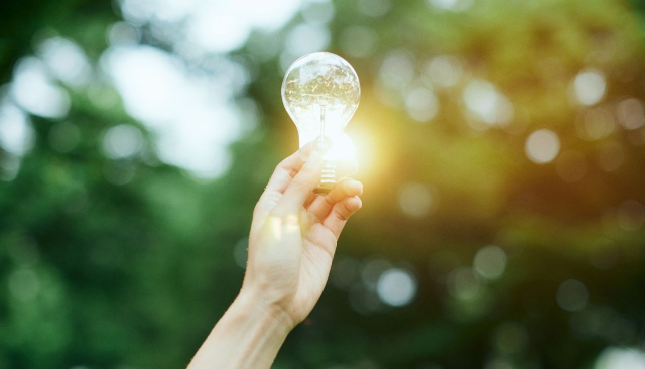 roka, kura tur spīdošu spuldzīti