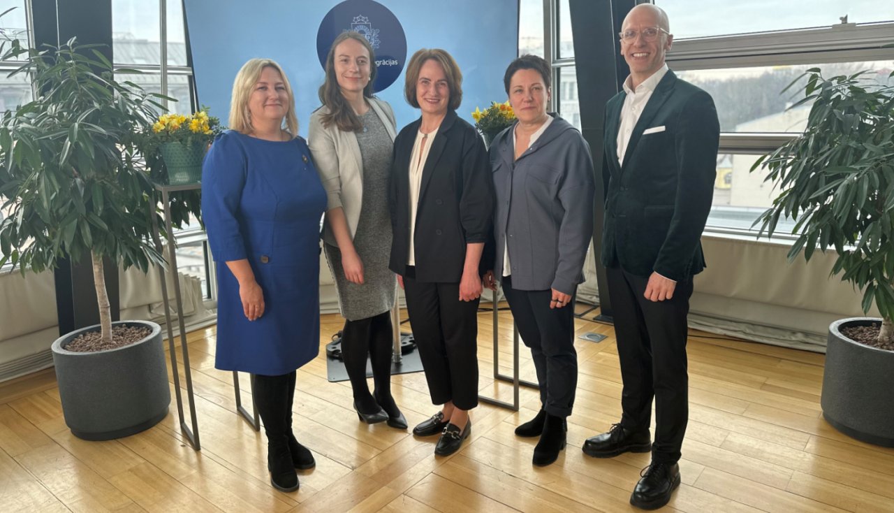 Stāv un pozē fotogrāfam četras dāmas un viens slaids un garš kungs