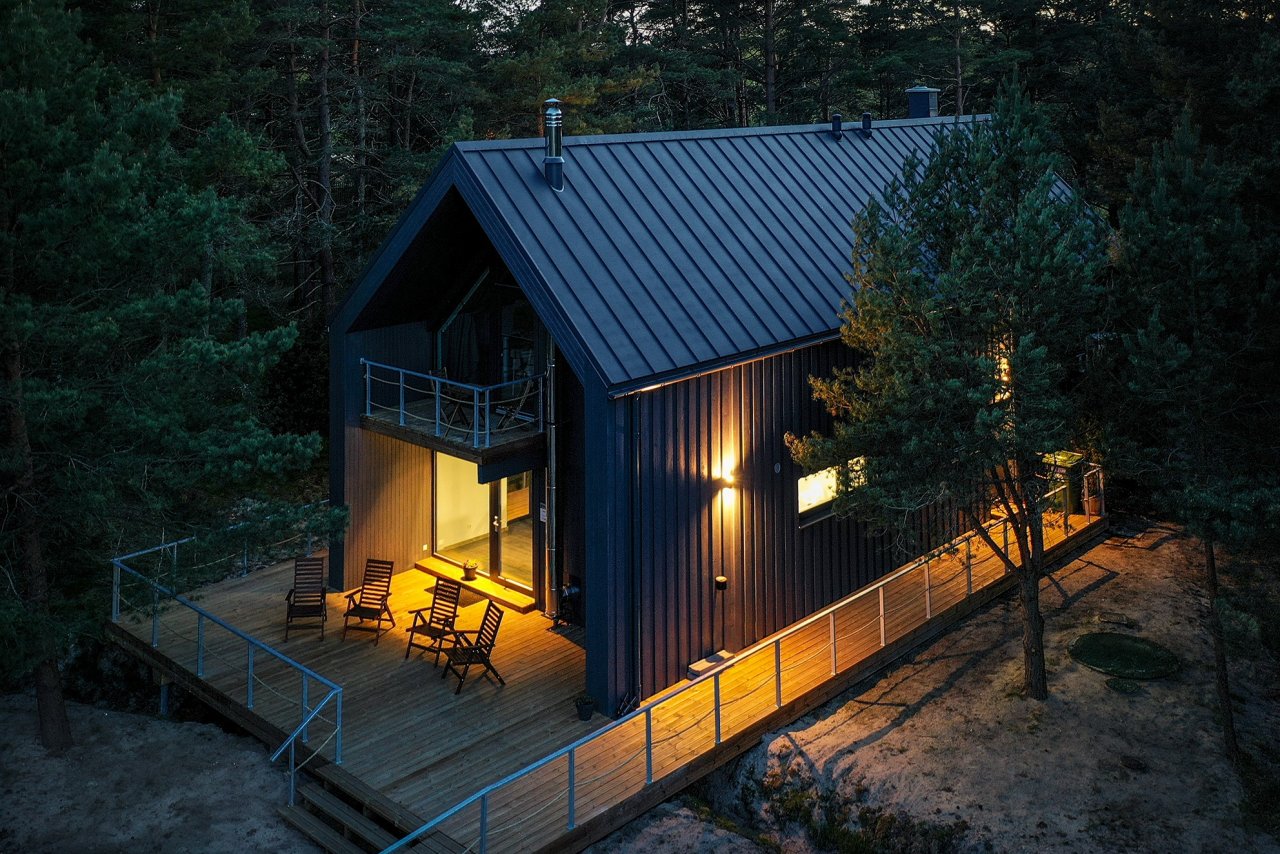 Brūna divstāvīga viesu māja ar gaismu logos no drona skata