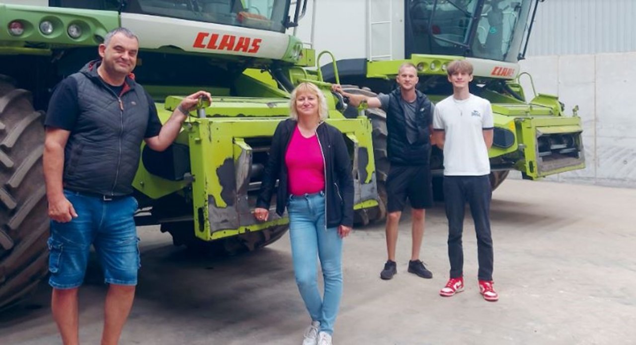 4 cilvēki stāv pie diviem zaļiem Claas kombainiem